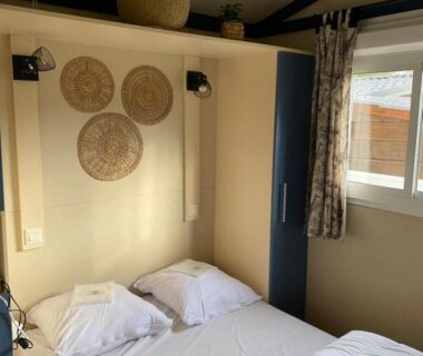 Chambre avec lit double paniers muraux et fenêtre dans le Mobilhome Chalet Ruoms