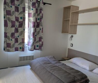 Chambre avec lit et rideaux dans le Mobilhome Claouey