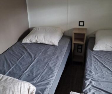 Intérieur du mobilhome avec deux lits simples et table de chevet du Mobilhome Clim Télé La Falaise 4 étoiles