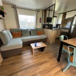 Salon avec canapé table basse et kitchenette dans le mobilhome L’Instant Chill au Cap Ferret