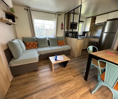 Salon avec canapé table basse et kitchenette dans le mobilhome L’Instant Chill au Cap Ferret