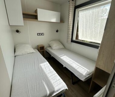 Chambre avec deux lits simples et fenêtre dans le mobilhome L'Instant Chill