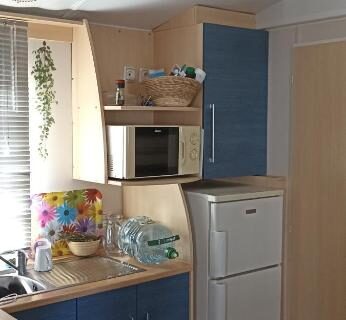 Coin cuisine avec réfrigérateur micro-ondes et plaque de cuisson dans le Mobilhome L'Oasis Camping le Clos Cottet