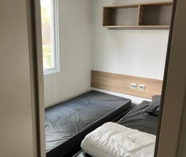 Chambre avec deux lits simples et couette pliée dans le mobilhome La Carabasse Vias Plage