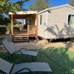 Terrasse en bois avec transats sur pelouse devant le mobilhome La Carabasse Vias Plage