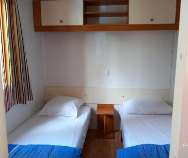 Chambre avec deux lits simples et chevet dans le mobilhome Les volets bleus