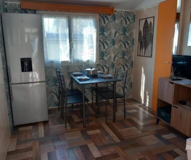 Intérieur avec coin repas réfrigérateur et télévision du mobilhome Les volets bleus