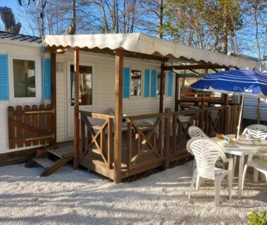 Terrasse couverte avec table et parasol du Mobilhome Les volets bleus