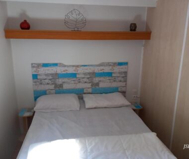Chambre du mobilhome avec lit double et tête de lit décorée du Mobilhome Les volets bleus
