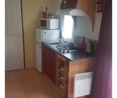 Intérieur avec coin cuisine réfrigérateur micro-ondes et plaque de cuisson dans le Mobilhome M 4 à 6 personnes