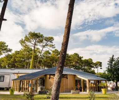 Bâtiment en bois et pins dans le camping Mobilhome Mag Ced les Dunes de contis Piscines et Plage