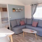 Séjour avec canapé d'angle et coin repas dans le Mobilhome Montourey 4 étoiles 3 chambres 2 salles de bain