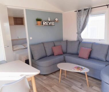 Séjour avec canapé d'angle et coin repas dans le Mobilhome Montourey 4 étoiles 3 chambres 2 salles de bain
