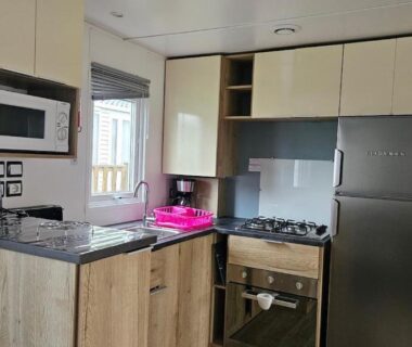 Cuisine équipée avec réfrigérateur four micro-ondes et évier dans le Mobilhome Normandie