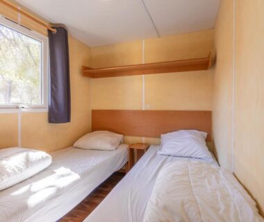 Chambre avec deux lits simples et fenêtre dans le Mobilhome Oasis village Puget