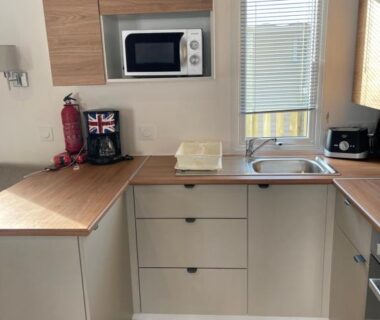 Coin cuisine avec évier plan de travail et micro-ondes dans le mobilhome Sables du midi