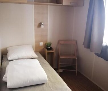Chambre avec lit simple table de chevet et chaise dans le Mobilhome Vendée Océan