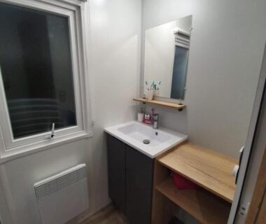 Salle de bain avec vasque miroir fenêtre et radiateur dans le Mobilhome a Gastes