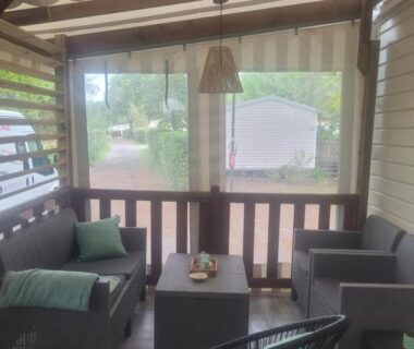 Terrasse couverte avec canapé fauteuil et table basse du Mobilhome a Gastes