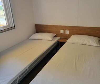 Chambre avec deux lits simples dans le mobilhome au bord de l'eau