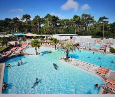 Piscine extérieure avec bassins et transats dans le camping Mobilhome au bord de l’eau