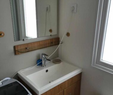 Salle d'eau avec lavabo miroir et lave-linge dans le Mobilhome au bord de l'eau