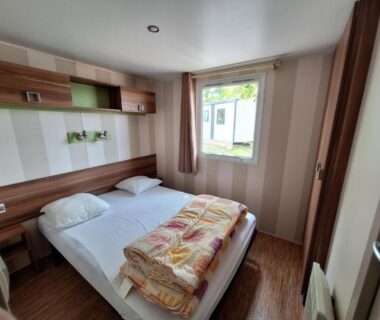 Chambre avec lit double et fenêtre dans le Mobilhome au bord du lac avec piscine