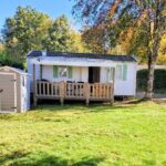Terrasse et pelouse devant mobilhome dans le camping Mobilhome au bord du lac avec piscine