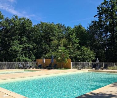 Bord de piscine avec chaises longues et parasols au Mobilhome au bord du lac avec piscine