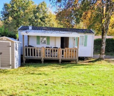 Terrasse et pelouse devant mobilhome dans le camping Mobilhome au bord du lac avec piscine