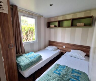 Chambre avec deux lits et fenêtre dans le mobilhome au bord du lac avec piscine