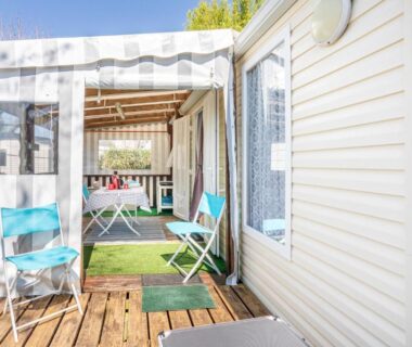 Terrasse en bois avec chaises et table dans la véranda du Mobilhome au calme piscine