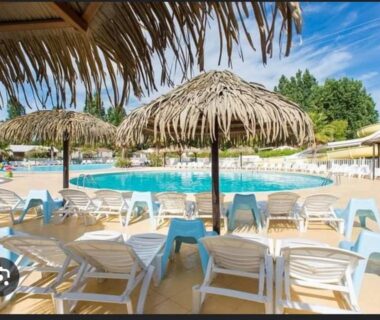 Piscine extérieure avec transats et parasols sous ciel bleu au Mobilhome beaux volumes ES40