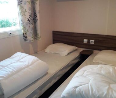 Chambre avec deux lits simples tête de lit et fenêtre dans le mobilhome ES40