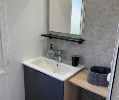 Salle de bain avec lavabo miroir étagère et panier dans le mobilhome bora bora