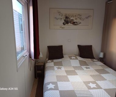 Chambre avec lit double et fenêtre dans le mobilhome Ernest Renan Louannec