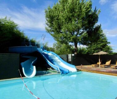 Piscine extérieure avec toboggan et chaises longues au mobilhome du camping Lalande Mimizan