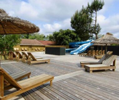 Terrasse en bois avec chaises longues et toboggans au Mobilhome camping Lalande Mimizan