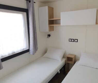 Chambre avec deux lits simples fenêtre et rangement dans le Mobilhome camping le BOSC