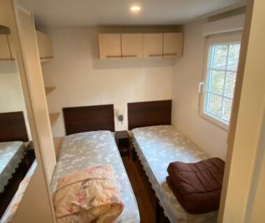 Intérieur chambre avec deux lits et fenêtre dans le Mobilhome comfort à la montagne