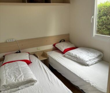 Chambre avec deux lits simples et fenêtre donnant sur l'extérieur dans le Mobilhome cosy 520