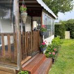 Terrasse couverte en bois avec jardinières sur la pelouse du Mobilhome cosy 520