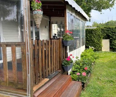 Terrasse couverte en bois avec jardinières sur la pelouse du Mobilhome cosy 520