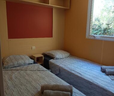 Chambre avec deux lits simples et fenêtre sur végétation du Mobilhome dans camping 3 étoiles en Provence
