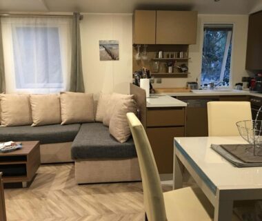 Salon avec canapé, cuisine et table dans le Mobilhome familial Saint Brévin Les Pierres Couchées