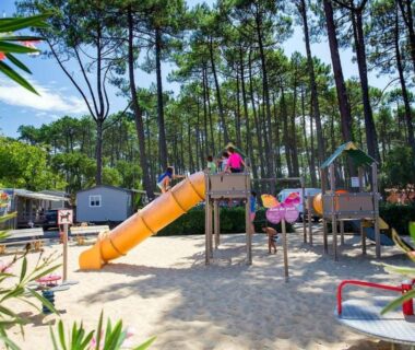 Aire de jeux sablonneuse sous les pins avec toboggan et balançoires au Mobilhome haut de gamme XXL