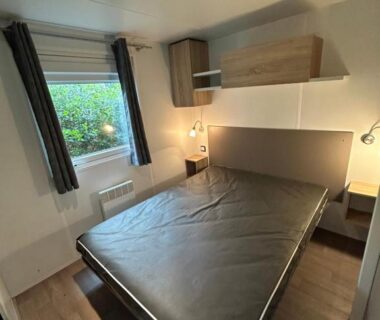 Chambre avec lit double et fenêtre dans le mobilhome les 3C de mimizan