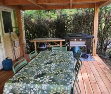 Terrasse couverte avec table, chaises et barbecue du Mobilhome les pieds dans l eau