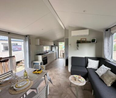 Intérieur avec canapé, coin repas et cuisine dans le mobilhome neuf au camping La Réserve