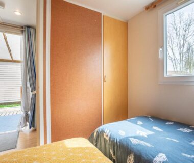 Intérieur chambre avec deux lits et porte donnant sur terrasse dans le mobilhome Mobilhome – piscines – terrasse